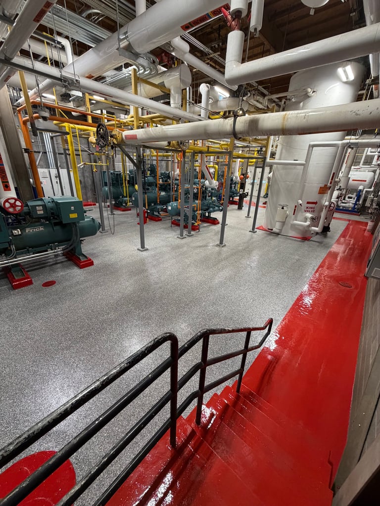 Industrial gym facility with yellow exercise equipment, silver pipes overhead, red platform edge, and concrete flooring