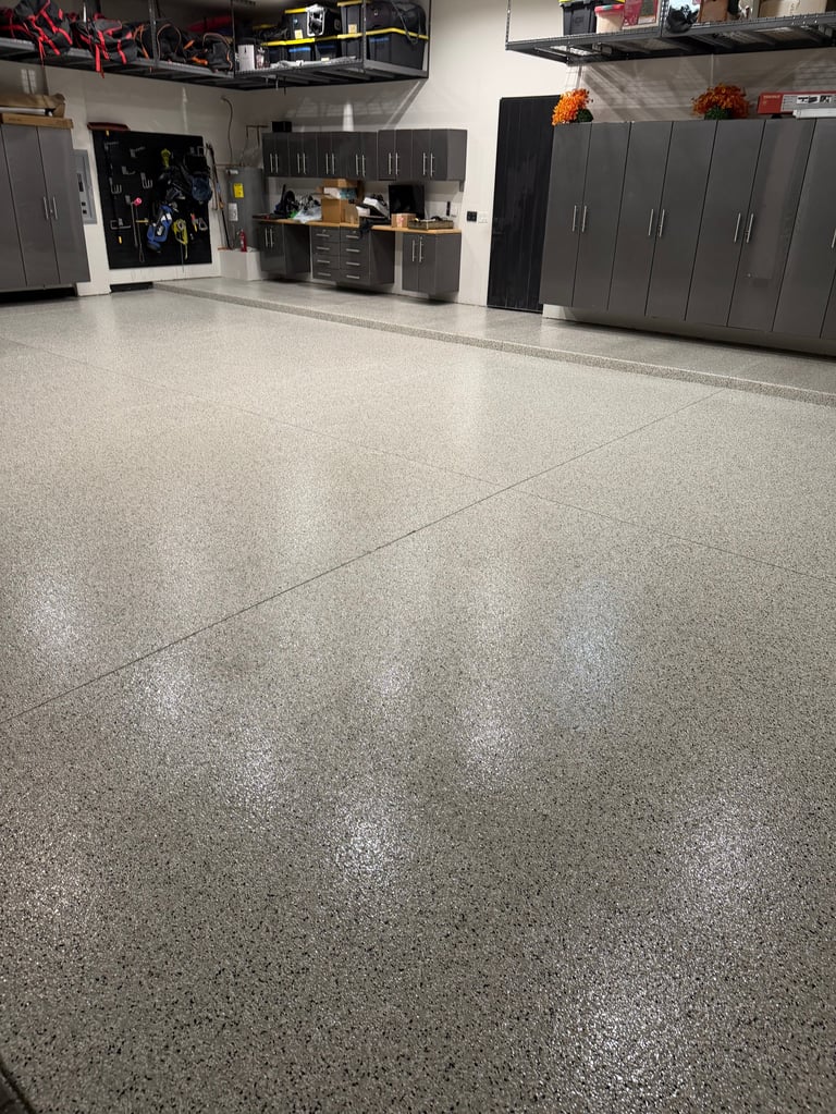 Modern garage interior with polished concrete floor, gray cabinets, workbench, and storage units along the walls