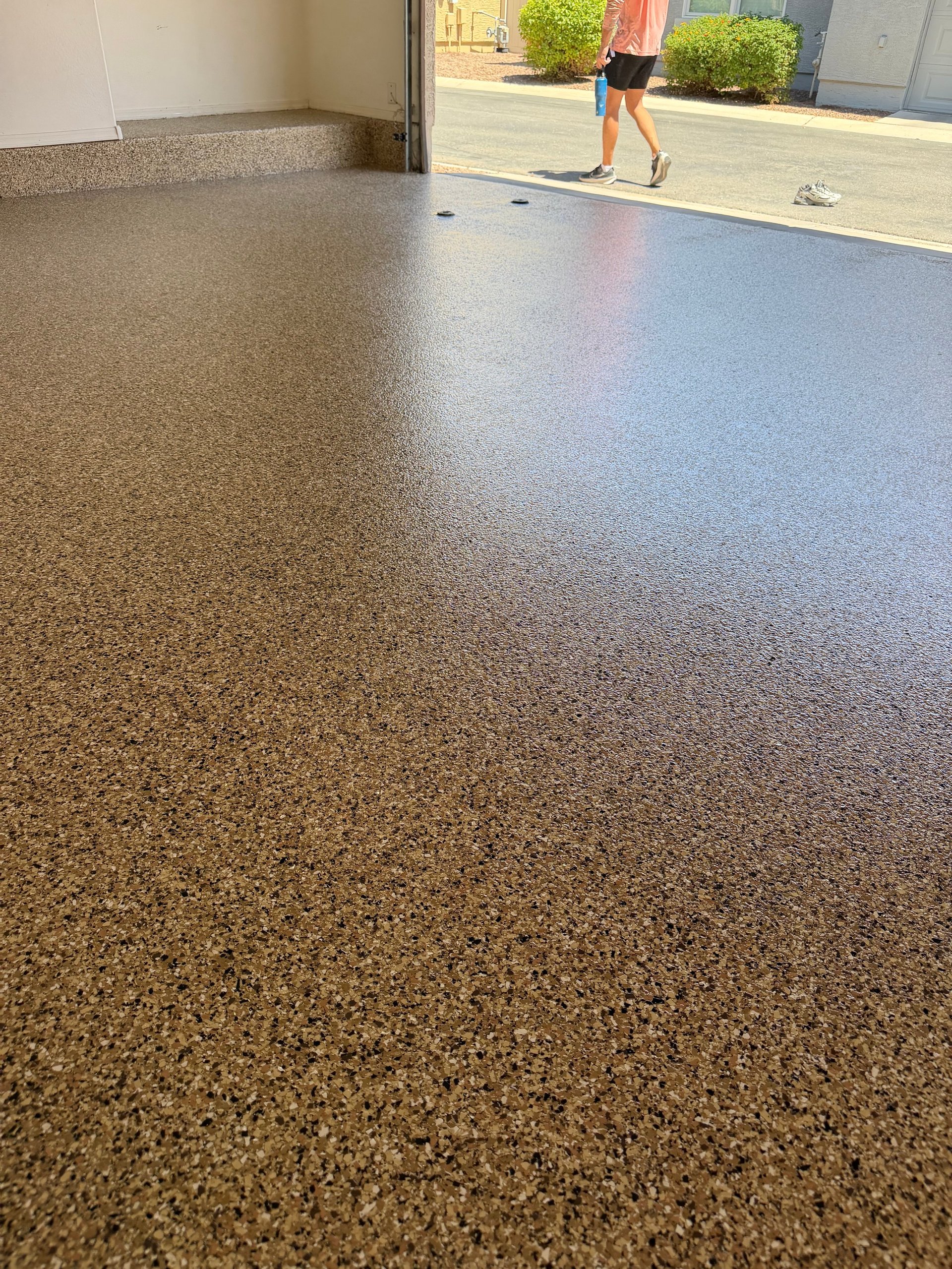 Polished concrete garage floor with runner visible outside and person jogging in background