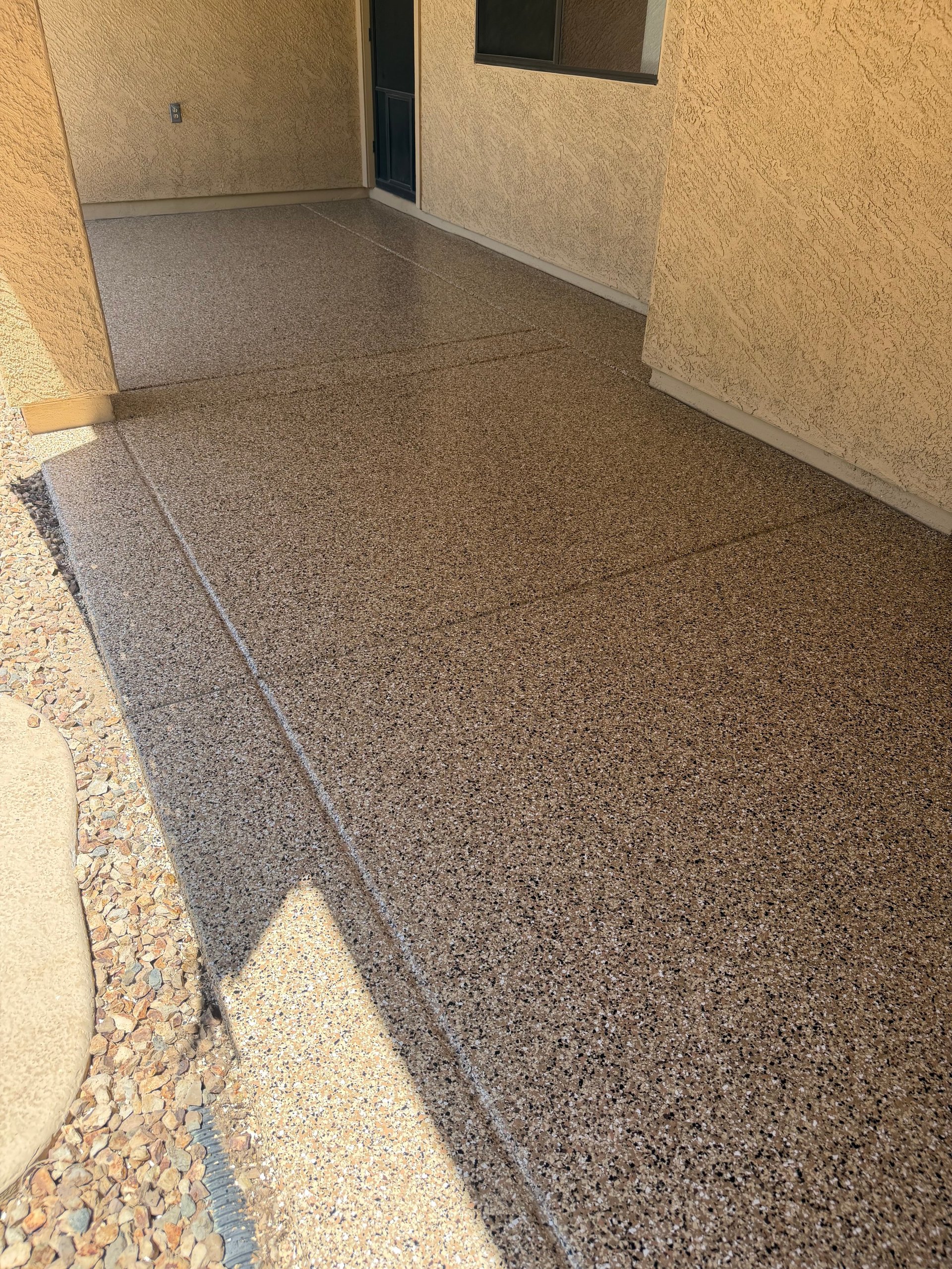 Newly installed gray concrete floor in an unfinished room with tan walls and doorway